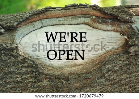 Text sign We're open on tree trunk background. End of COVID-19 quarantine message. Hotel, cafe, restaurants, local shops, service owners welcoming guests after people shutdown in coronavirus outbreak.