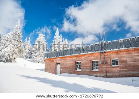 Snow covered wooden hut in the mountains, nice weather.