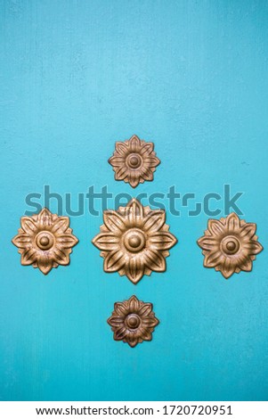 Turquoise wall with ornaments flowers in gold. Texture.