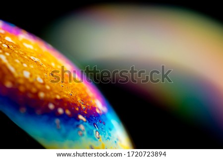 Psychedelic abstract planet from soap bubble, Light refraction on a soap bubble, Macro Close Up moving particles Rainbow colors on a black background. Model of Space or planets universe cosmic galaxy.