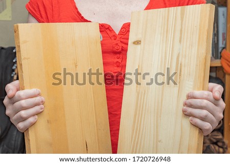 The girl whose face is not visible holds an empty wooden boards in her hands