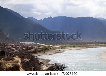 Blue sky and white clouds, distant mountains, green water, sandbars and trees by the river, like beautiful pictures