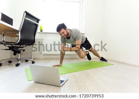 Man Doing Exercises at Home with Online Tutorial. Man Watching Laptop Doing Sports. Video Call Practice. Online Training on Quarantine at Home. Home Sport, Healthy Life, Quarantine Concept Royalty-Free Stock Photo #1720739953