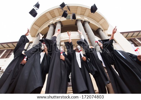 group of happy graduates throwing graduation hats in the air celebrating Royalty-Free Stock Photo #172074803
