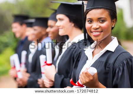 pretty african female college graduate at graduation with classmates