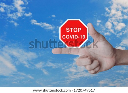 Hand pressing stop COVID-19 outbreak icon plate over blue sky with white clouds, Global epidemic alert, Concept of novel coronavirus outbreak