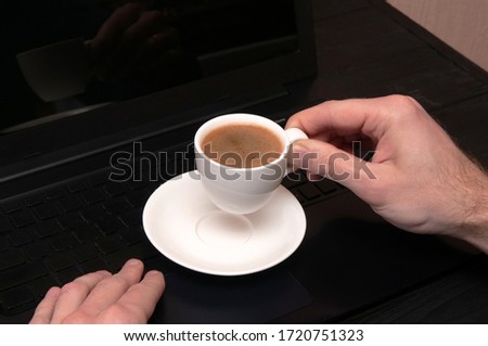 coffee break concept, close up white cup of coffee in male hands above black notebook