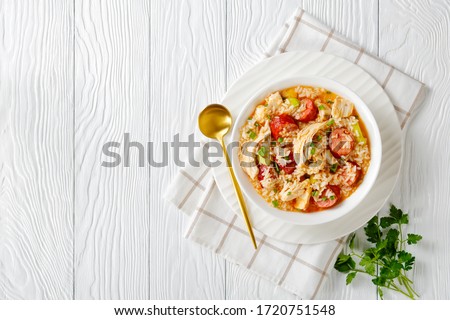 South American stew chicken bog with smoked sausage, rice, leek, cooked in chicken broth served on a white plate sprinkled with green onion on top on a white wooden background, top view, copy space