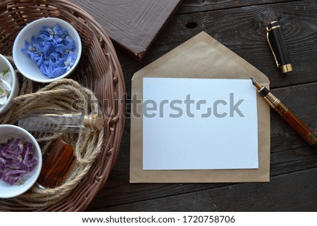 Artistic mockup for your artwork with beautiful flowers, kraft paper envelope and empty card  shot from the top. Flat lay composition 
with space for text. Perfumer set.