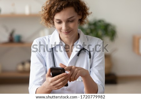 Young female physician using mobile healthcare tech app consulting remote patient online in telemedicine software. Woman doctor therapist holding smart phone texting message for digital consultation.
