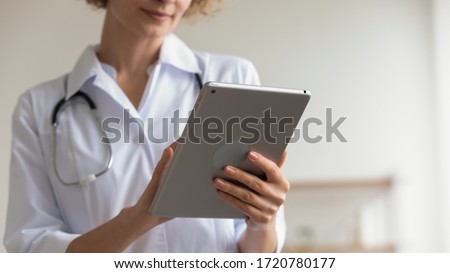 Female professional medic doctor holding modern pad using digital tablet remote telemedicine app in hospital working online. Healthcare technology telehealth ehealth concept. Close up view, copy space Royalty-Free Stock Photo #1720780177