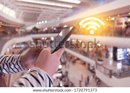 Woman hand using smartphone with wifi icon in public place outdoor background. Business communication social network concept. Royalty-Free Stock Photo #1720791373