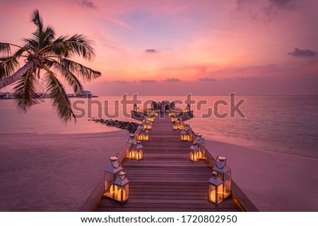 Romantic dinner on the beach with sunset, candles with palm leaves and sunset sky and sea. Amazing view, honeymoon or anniversary dinner landscape. Exotic island evening horizon, romance for a couple  Royalty-Free Stock Photo #1720802950