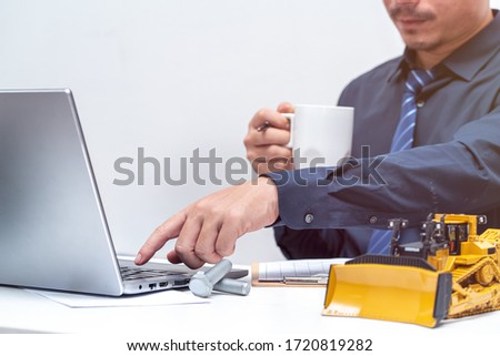 Professional engineer reaching hand to laptop for during working day in office, repair maintenance heavy machinery concept