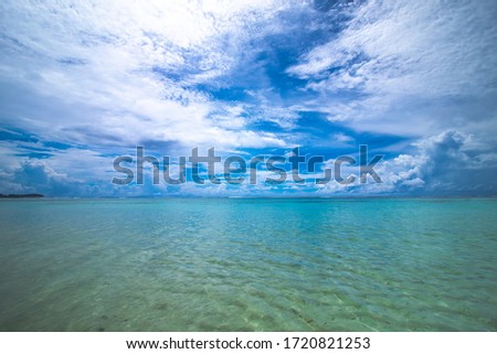clear beach water with blue sky and clouds