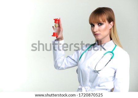 woman doctor holds hourglass on gray background