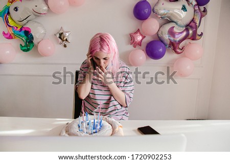 Girl celebrating her birthday, talking on the phone and testing the cake during quarantine due to covid-19 virus