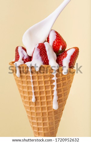 in the waffle cone, whole strawberries covered with a dripping white yogurt cream