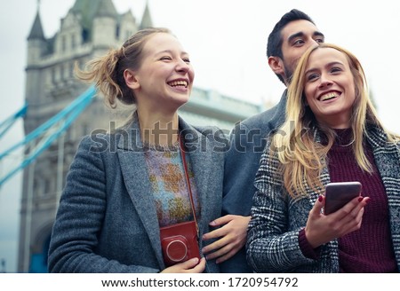 Group of happy young friends having fun on city street. Group of millennial people walking through city park together, near of  bridge. Travel and friendship concept - Image