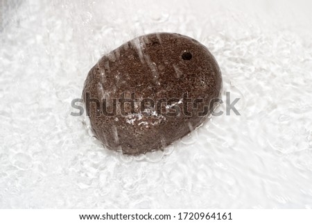 Spa pumice oval shaped under a stream of water on a white background. Home Body Care Supplies