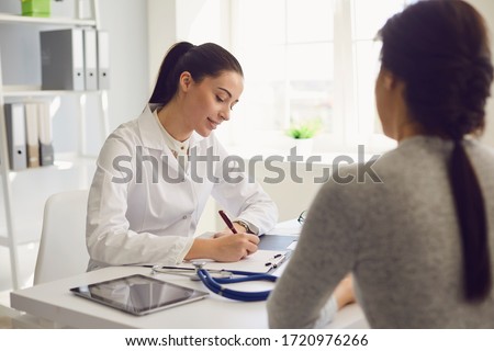 Woman patient visiting female doctor at clinic office. Medical work writes a prescription on a table in a hospital. Royalty-Free Stock Photo #1720976266