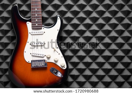 Top view of electric guitar on lying acoustic foam panel background, with copy space at right