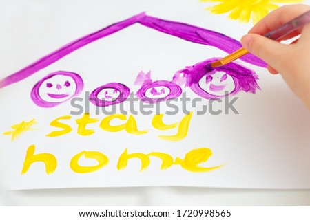 Child is drawing family under a roof with words Stay Home on sheet of paper. Children creativity.