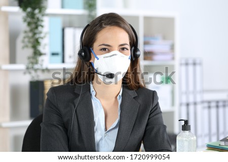 Happy telemarketer woman posing looking at camera avoiding covid-19 with mask sitting at the office Royalty-Free Stock Photo #1720999054