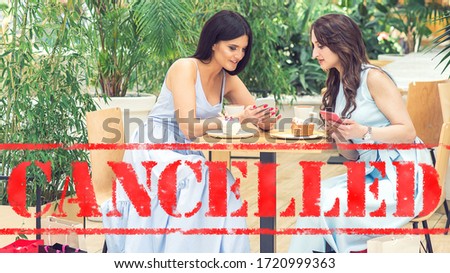 Word CANCELLED on background of two young women in the cafe outdoors. Coronavirus quarantine. Closed cafe outdoors.