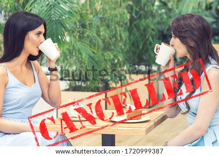 Word CANCELLED on background of two young women in the cafe outdoors. Coronavirus quarantine. Closed cafe outdoors.