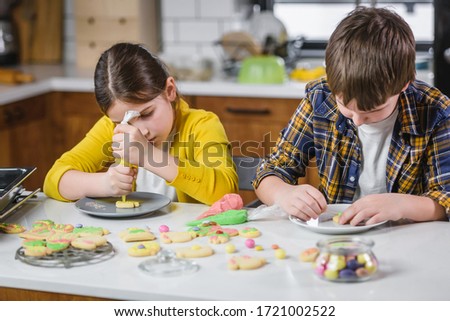 Children decorating cookies with sugar icing for holidays