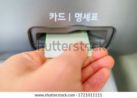 hand inserting card into ATM (Korean character on the picture mean card and receipt)
