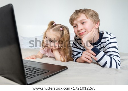 Two kids girl and boy using laptop computer at home and smiling