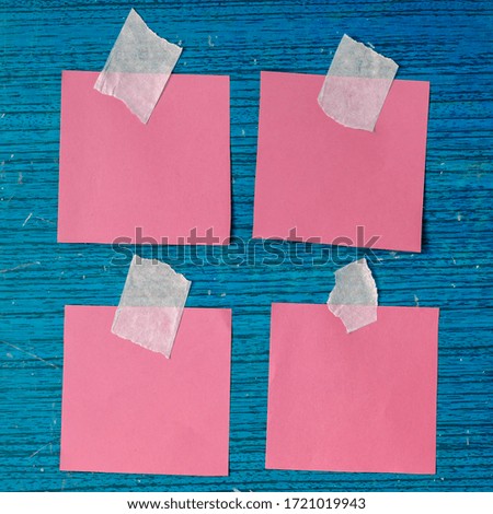 Creative blue background with colored paper. Four pieces of pink paper glued with sticky tape to the board. Blue wooden background with scratches and scuffs. Training, business, information.