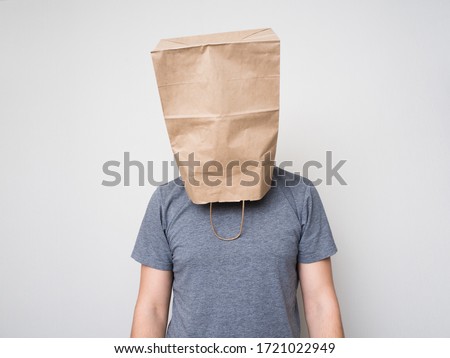 A man in a gray shirt and a paper bag on his head.
