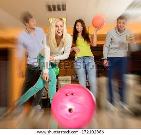 Group of four young smiling people playing bowling 