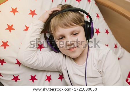 Young boy listening to music on headphones. Children at home during coronavirus. Distance learning.
