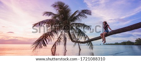 Woman in hat sitting on the beach palm and looking on beautiful sunset. Banner edition.