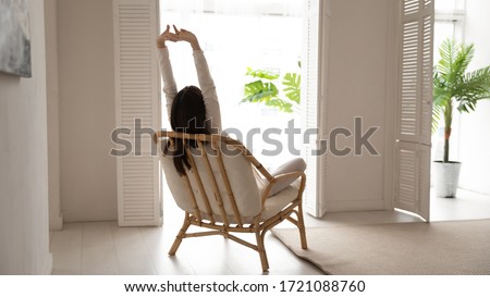 Back view of young woman sit relax in chair at home stretch after good sleep or nap, relaxed girl rest in armchair in living room, do morning exercise, relieve negative emotion, stress free concept Royalty-Free Stock Photo #1721088760