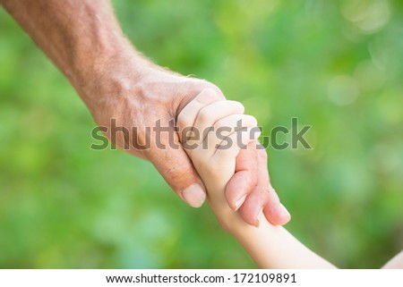 Senior man holding young child by the hands outdoors
