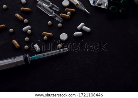 top view on a medical table. The black table on it are pills, syringe, ampoules, and chestnut. copy space.