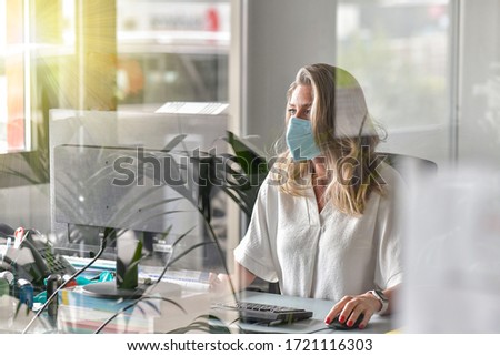 Executive woman working at her desk and wearing a protective mask against covid-19 Royalty-Free Stock Photo #1721116303
