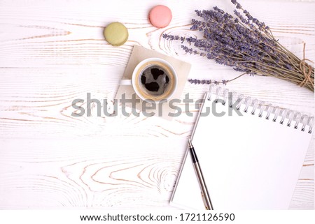 Composition from blank diary, cup of coffee and macaroon and lavender flowers on a white shabby wooden table. Fashion flat lay, copy space.