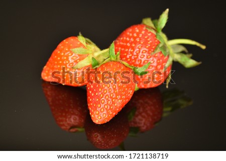 Three bright red sweet strawberries, close-up, on a black background.