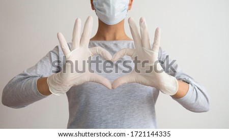 A nurse with a medical mask and gloves gives a symbol of the heart. Royalty-Free Stock Photo #1721144335
