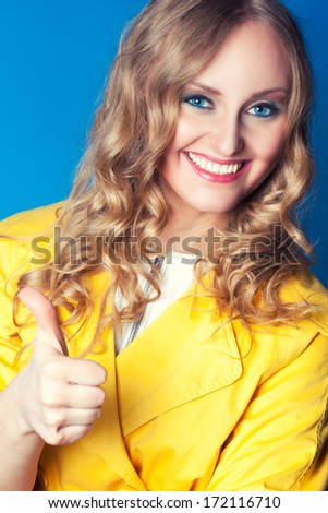 Beautiful and happy woman with thumbs up on blue background
