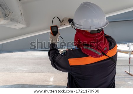Technicians are measuring the Dry Film Thickness (DFT) for fireproof painting of steel structure work in industrial factory.  Royalty-Free Stock Photo #1721170930