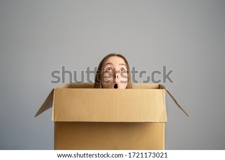Smart idea.. Teenager student girl sitting inside cardboard box  looking up having bright idea or plan. Think outside the box concept. Out of comfort zone. 
