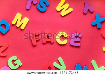 Word FACE From Plastic Magnetic Letters On Red Background