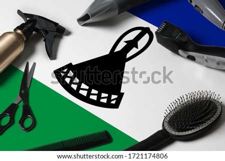 Lesotho flag with hair cutting tools. Combs, scissors and hairdressing tools in a beauty salon desktop on a national wooden background.